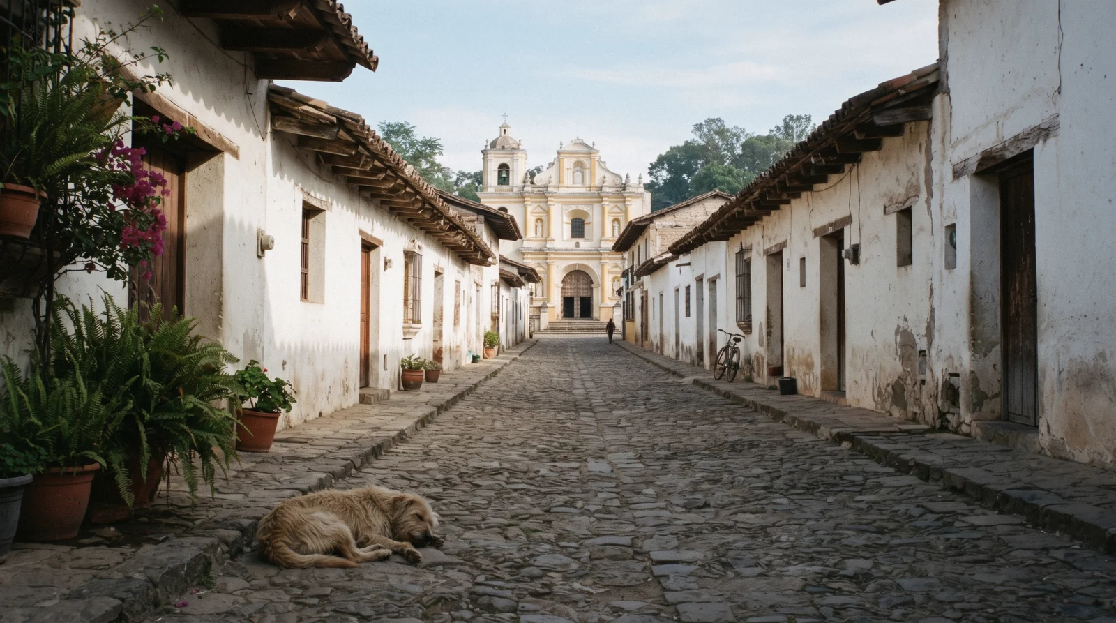 The low whitewashed houses and terracotta roofs of the San Felipe lane outside the grid of Antigua Guatemala, a church facade at the end of the street