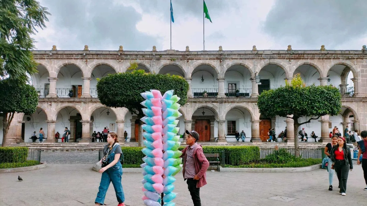 Walking tour group pausing under the Santa Catalina arch in Antigua Guatemala
